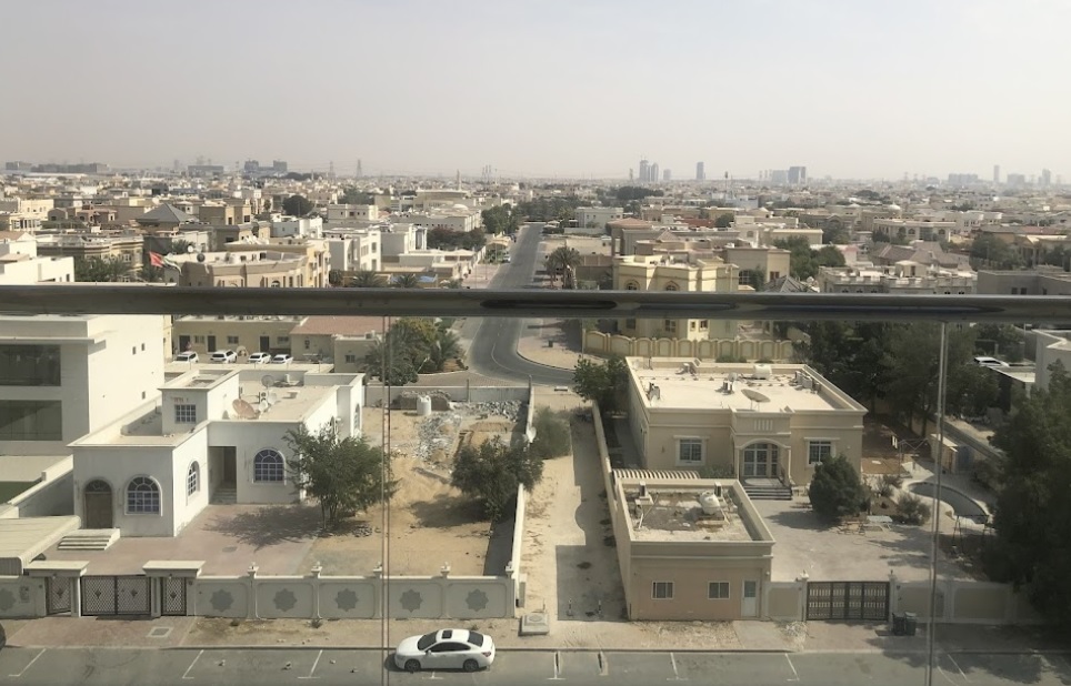 صورة من منطقة البرشاء تُظهر الأبراج السكنية الحديثة والشوارع الواسعة مع المساحات الخضراء والمراكز التجارية.