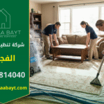 فريق عمل متخصص من شركة تنظيف سجاد في الفجيرة يقوم بتنظيف سجادة كبيرة بالبخار داخل غرفة معيشة منزلية، مع وجود عمال يحركون الأثاث وآخرين يستخدمون معدات حديثة.